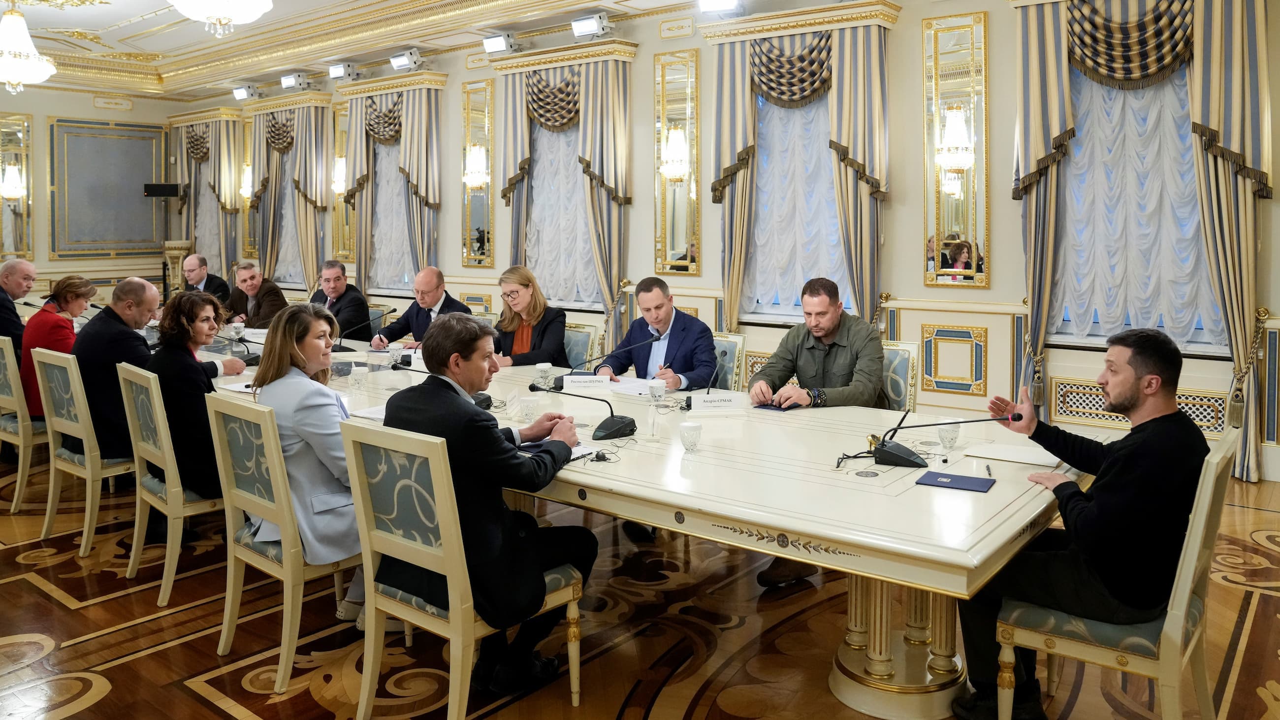 Män och kvinnor sitter runt ett bord och diskuterar